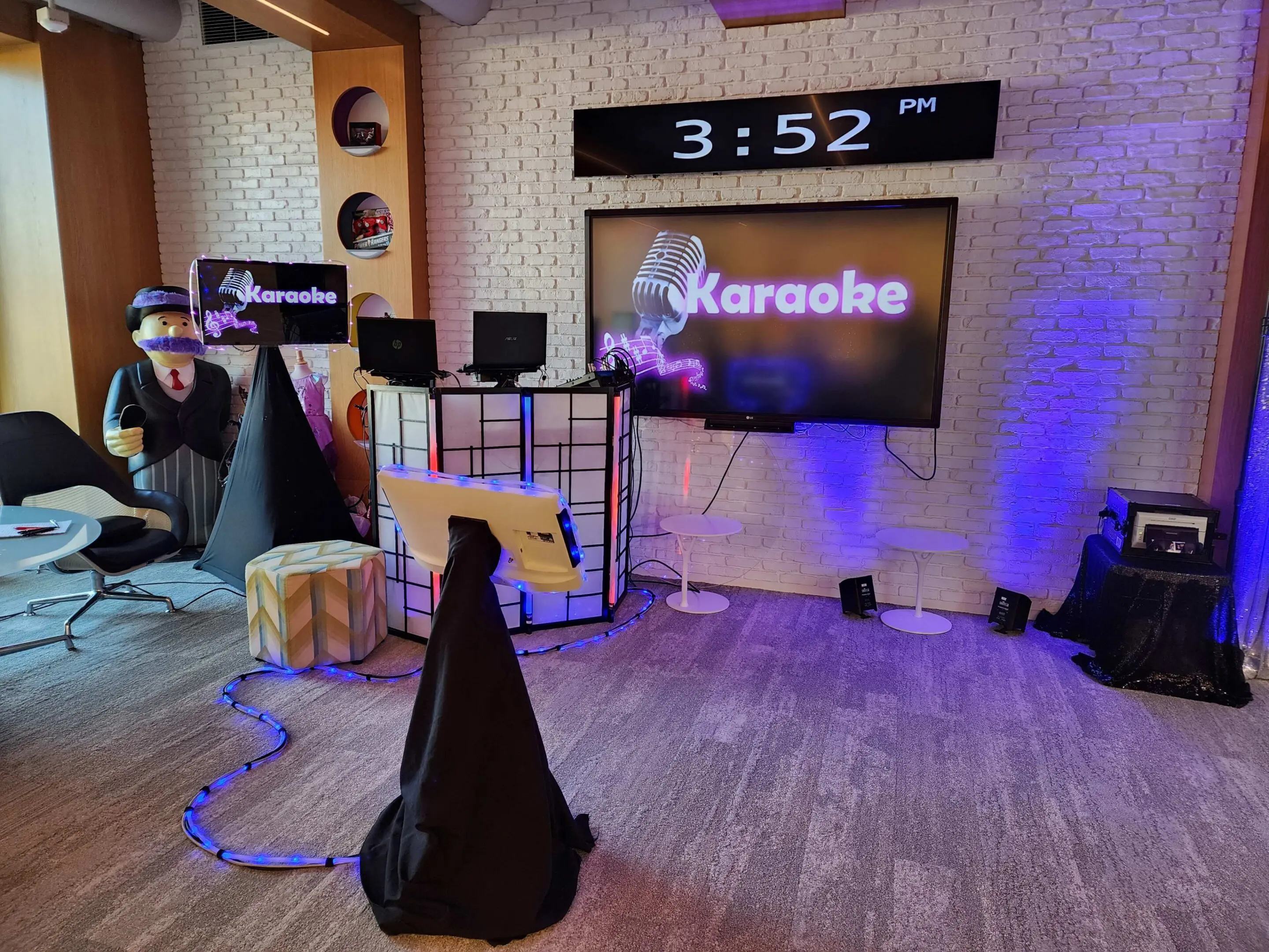 equipment by Mr Dj Services A modern karaoke dj setup in a room with a large screen displaying "Karaoke," two microphones, speakers at Hasbro Christmas Party.