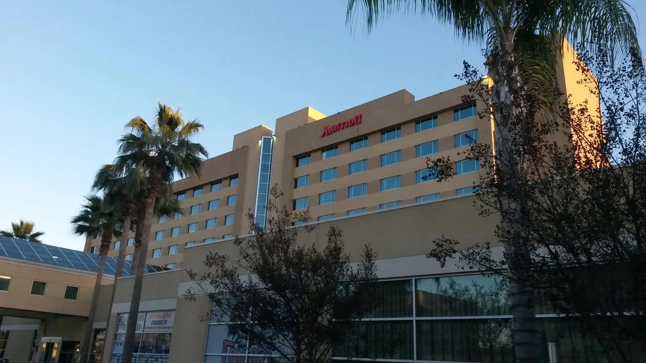 Mr Dj Services in Bakersfield A beige multistory Marriott hotel building with palm trees in front, viewed from ground level under a clear blue sky.
