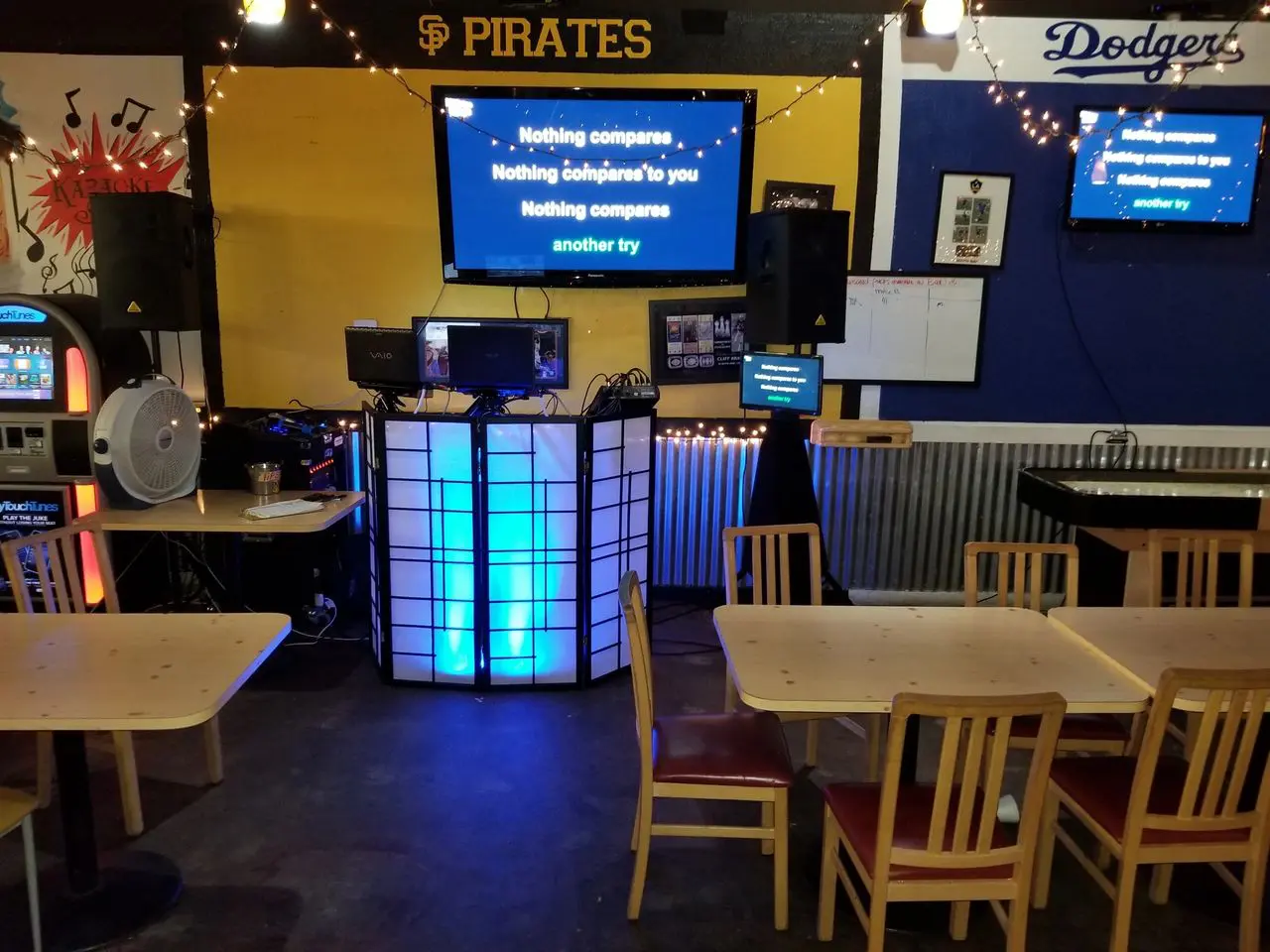 Mr Dj Services MVP Pizza A karaoke setup in a casual dining area with lyrics on TV screens, wooden tables and chairs, and sports team signs on the walls.
