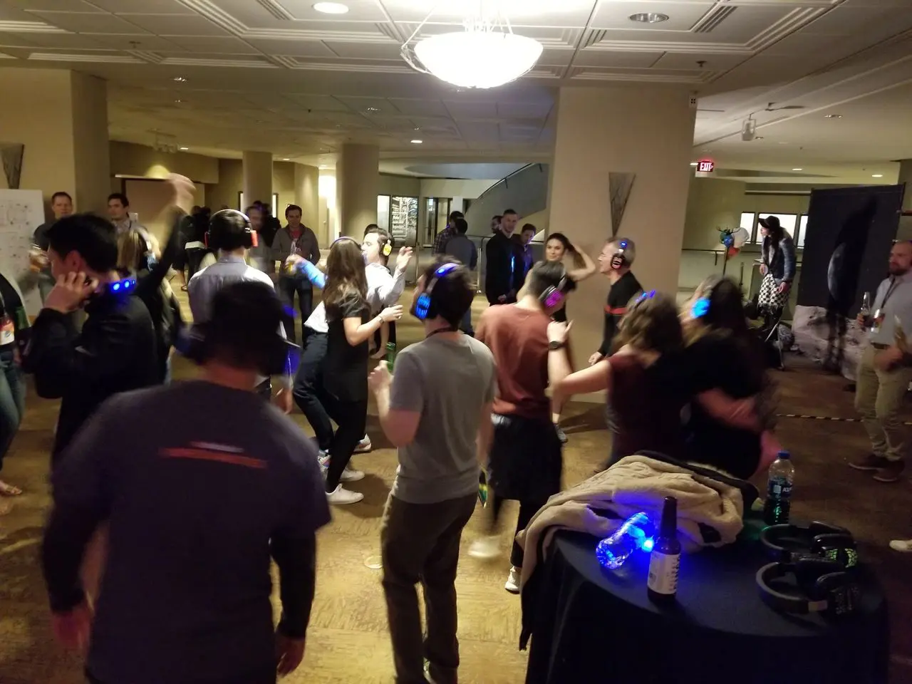 Silent Disco Party - Dj Services A group of people wearing headphones are dancing in a dimly lit room, likely participating in a silent disco event.